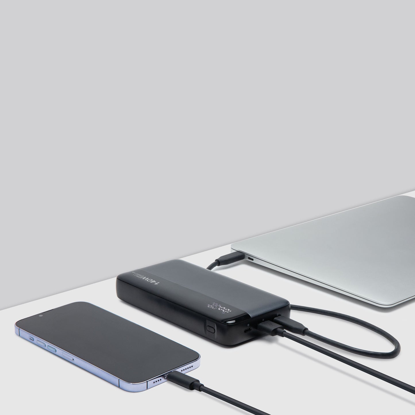 Linocell powerbank 140W 25000mAh sort, smartphone og laptop tilsluttet via ladekabler, sæt ovnfra.