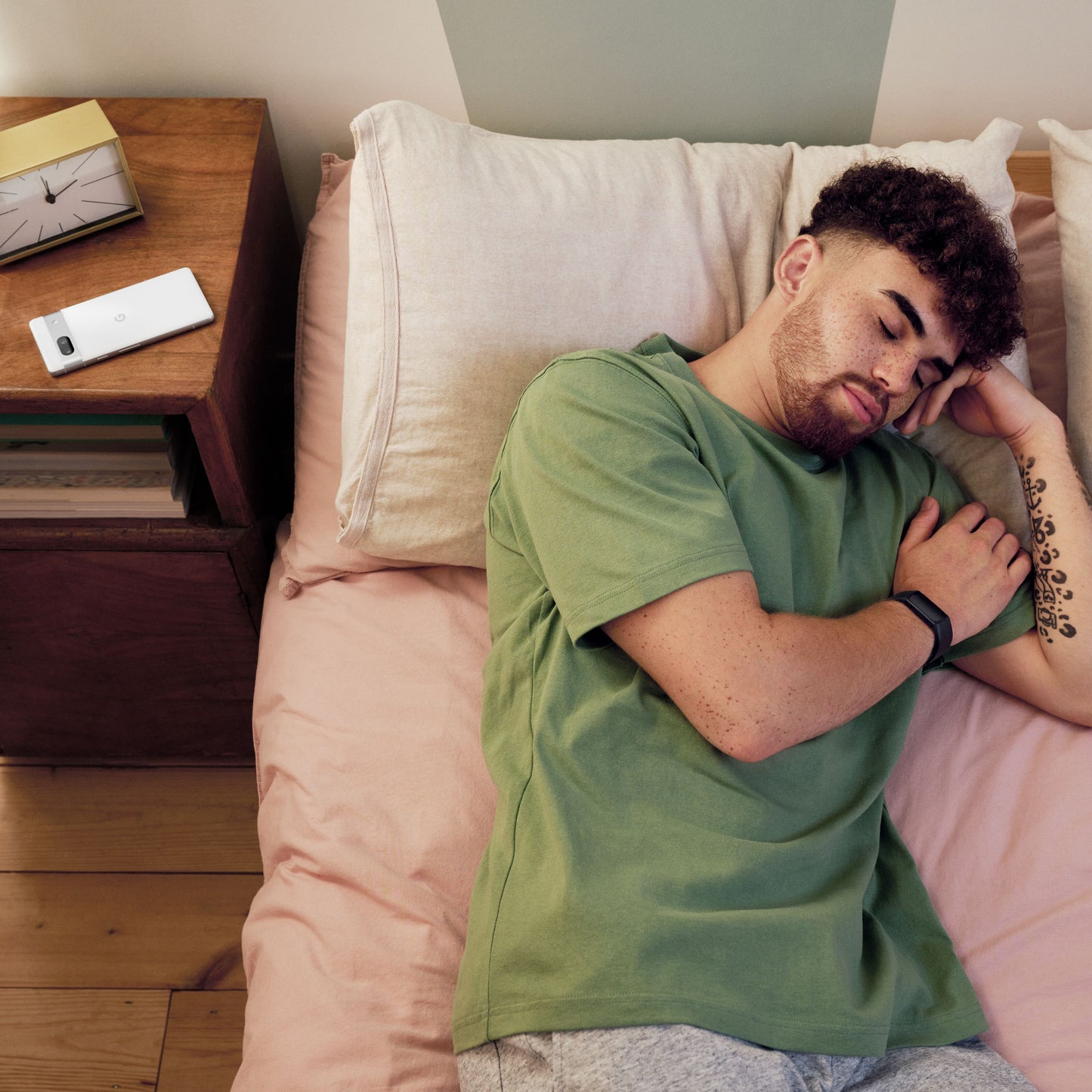 Fitbit Oplad 6 aktivitetsarmbånd sort vises på natbord ved siden af ur og telefon.