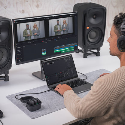 Røde Rode Trådløst PRO trådløst mikrofonsystem ved siden af laptop, storskærm og studiemonitorer på skrivebord.