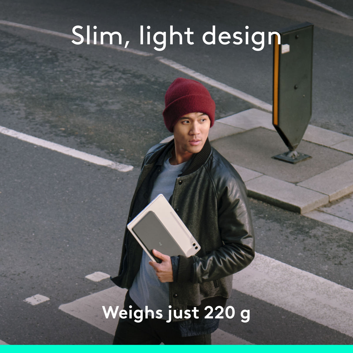 Et gråt Logitech Keys-To-Go 2 bærbart Bluetooth-tastatur, som en person holdt i hånden, mens vedkommende var på vej over gaden.