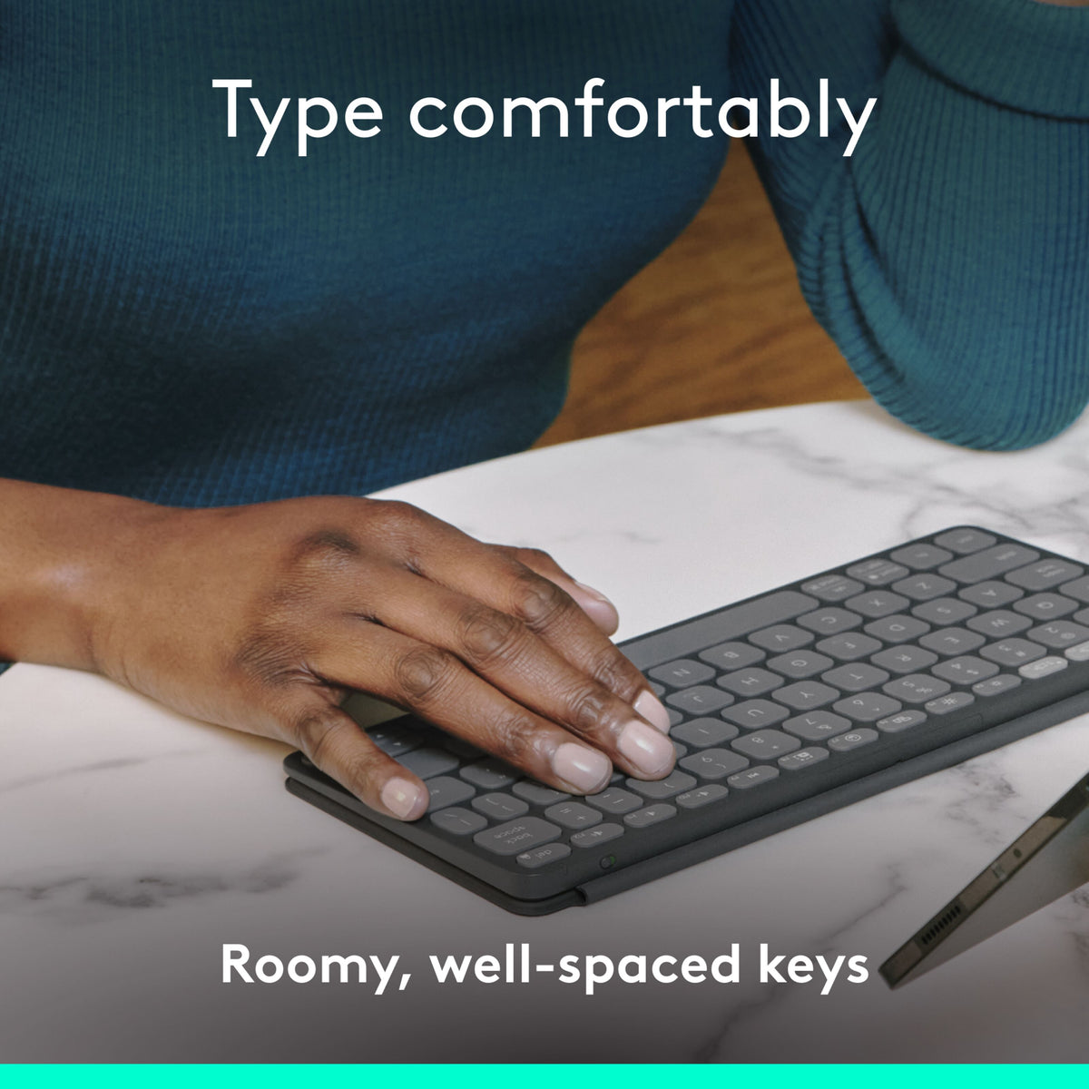 Logitech Keys-To-Go 2, et bærbart Bluetooth-tastatur, ligger på et marmorbord med teksten Skriv komfortabelt og Rummelige taster med god afstand.