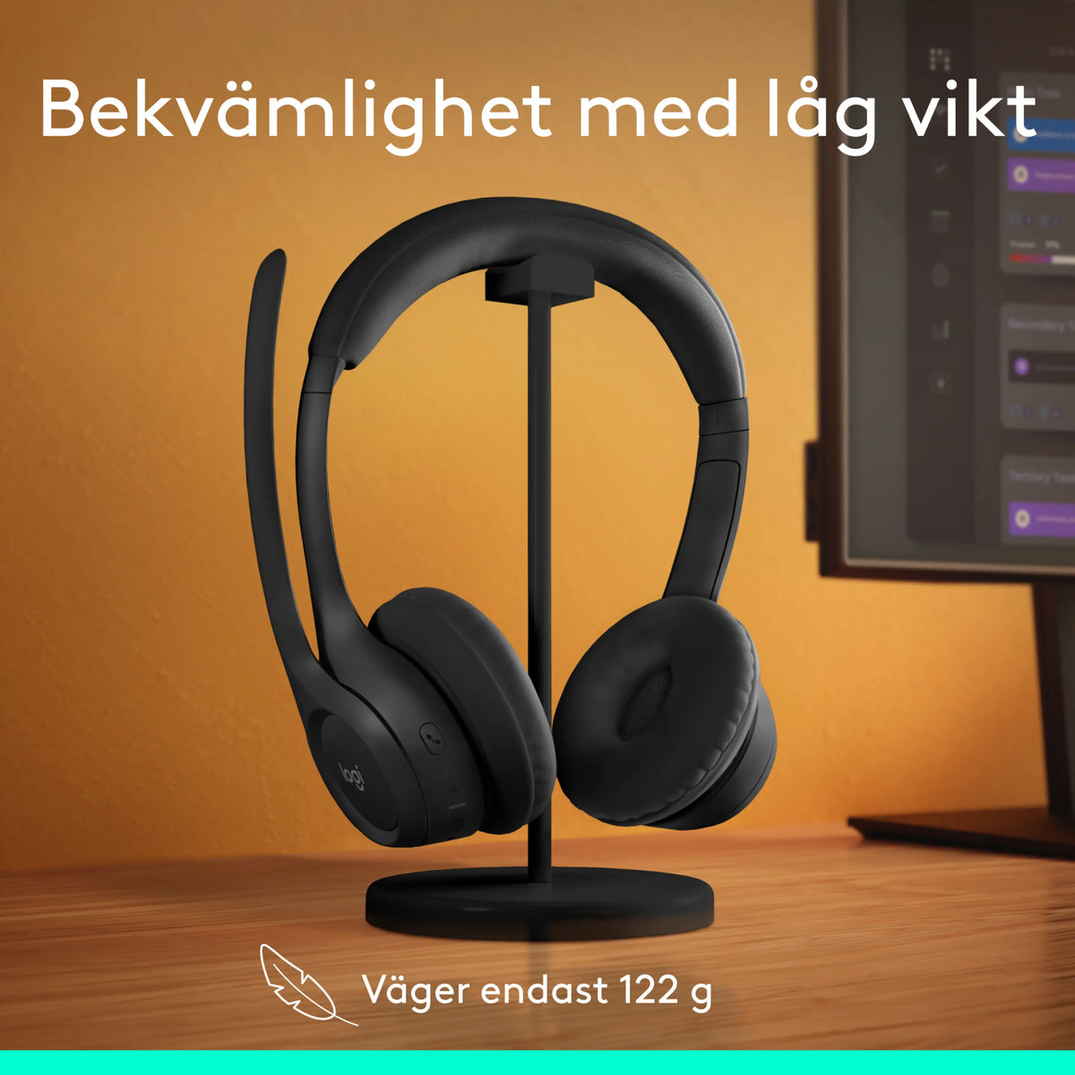 Logitech Zone 300 trådløst Bluetooth-headset i grafitfarve med mikrofonarm på en holder foran computerskærmen.