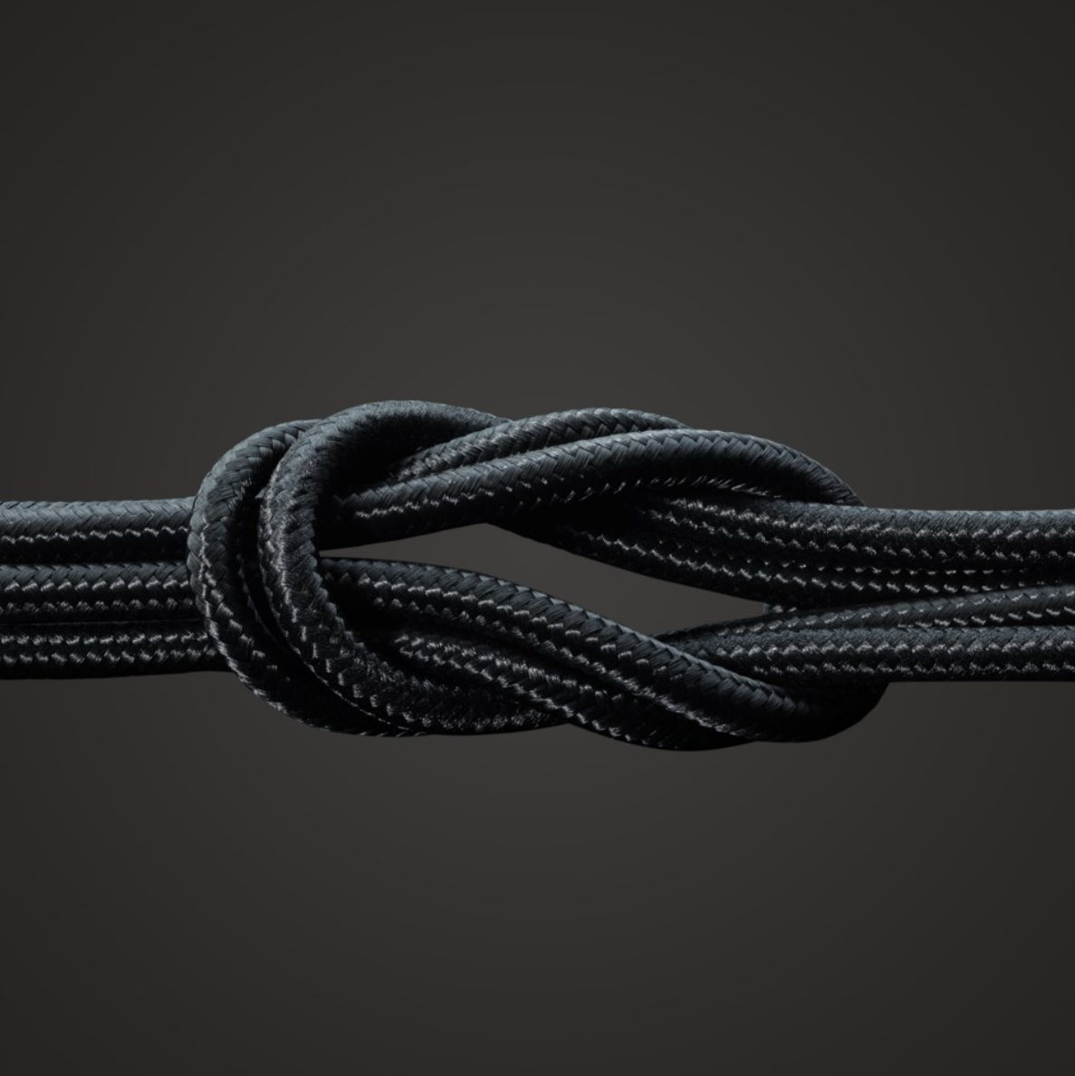 Linocell Kevlar USB-A til Lightning-kabel, MFi-certificeret, sort, 1 m, robust sort kabel i tæt knude på mørk baggrund.