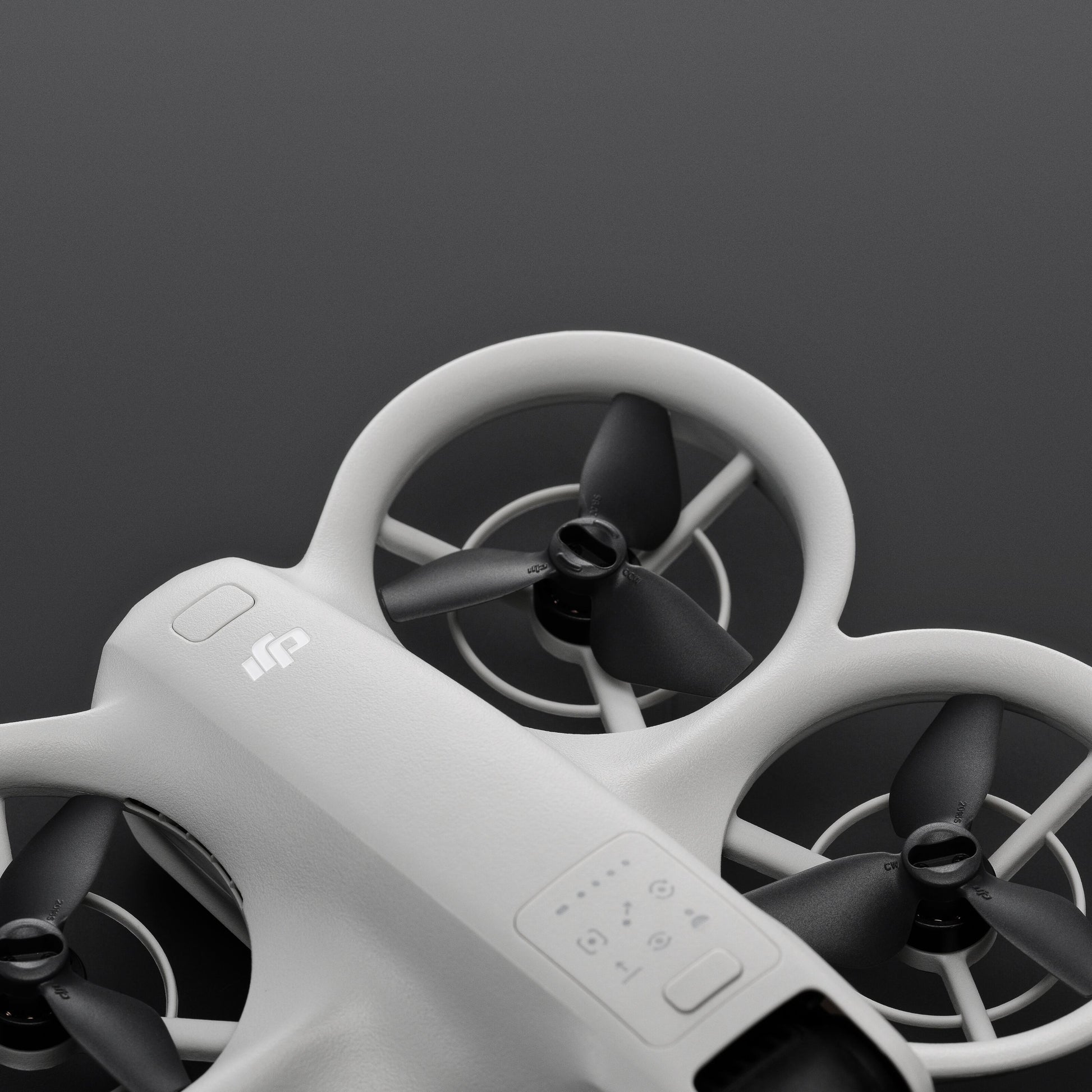 DJI Neo drone med tre slags propeller og synligt betjeningspanel, close-up mod mørk baggrund.