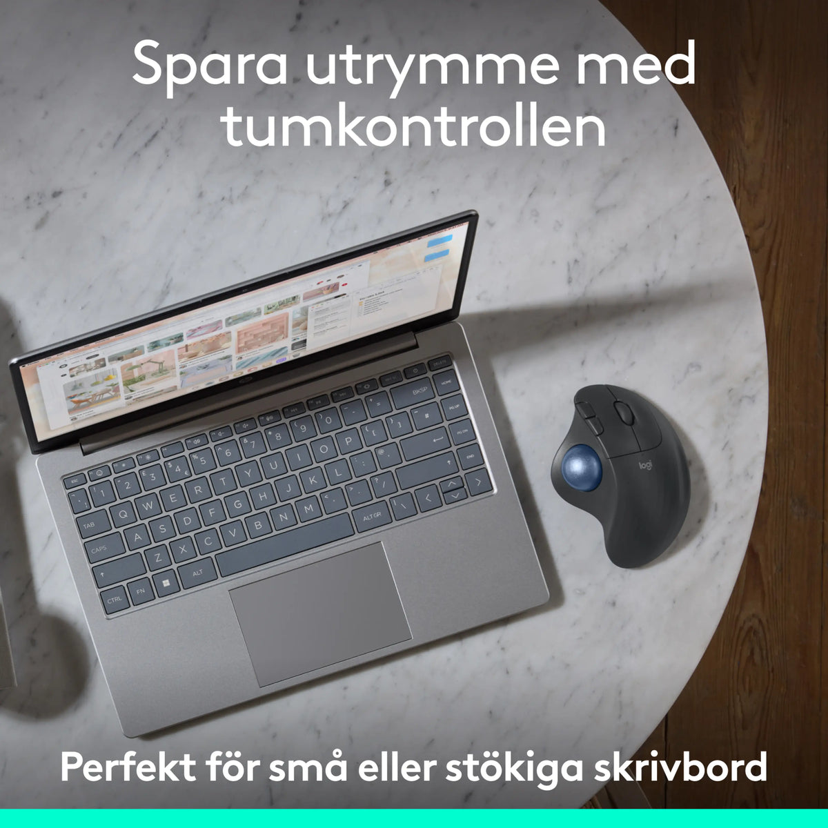 Logitech Ergo M575S trådløs trackball-mus i farven Graphite ved siden af en bærbar computer på et marmorbord.
