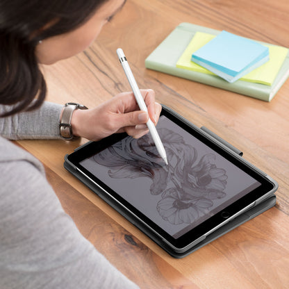 IPad 10,2 med Logitech Slim Folio tastaturcover og stylus bruges til at tegne, ses ved siden af lukket notesbog og sticky notes.
