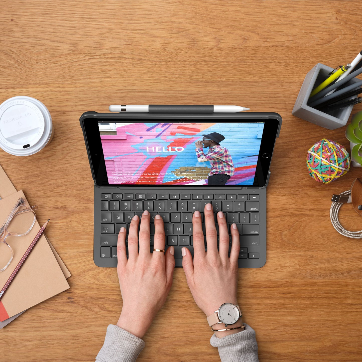 Logitech Slim Folio tastaturcover til iPad 10,2 med farverig "HELLO"-tekst på skærmen, vises fra skrivebordsvinkel.