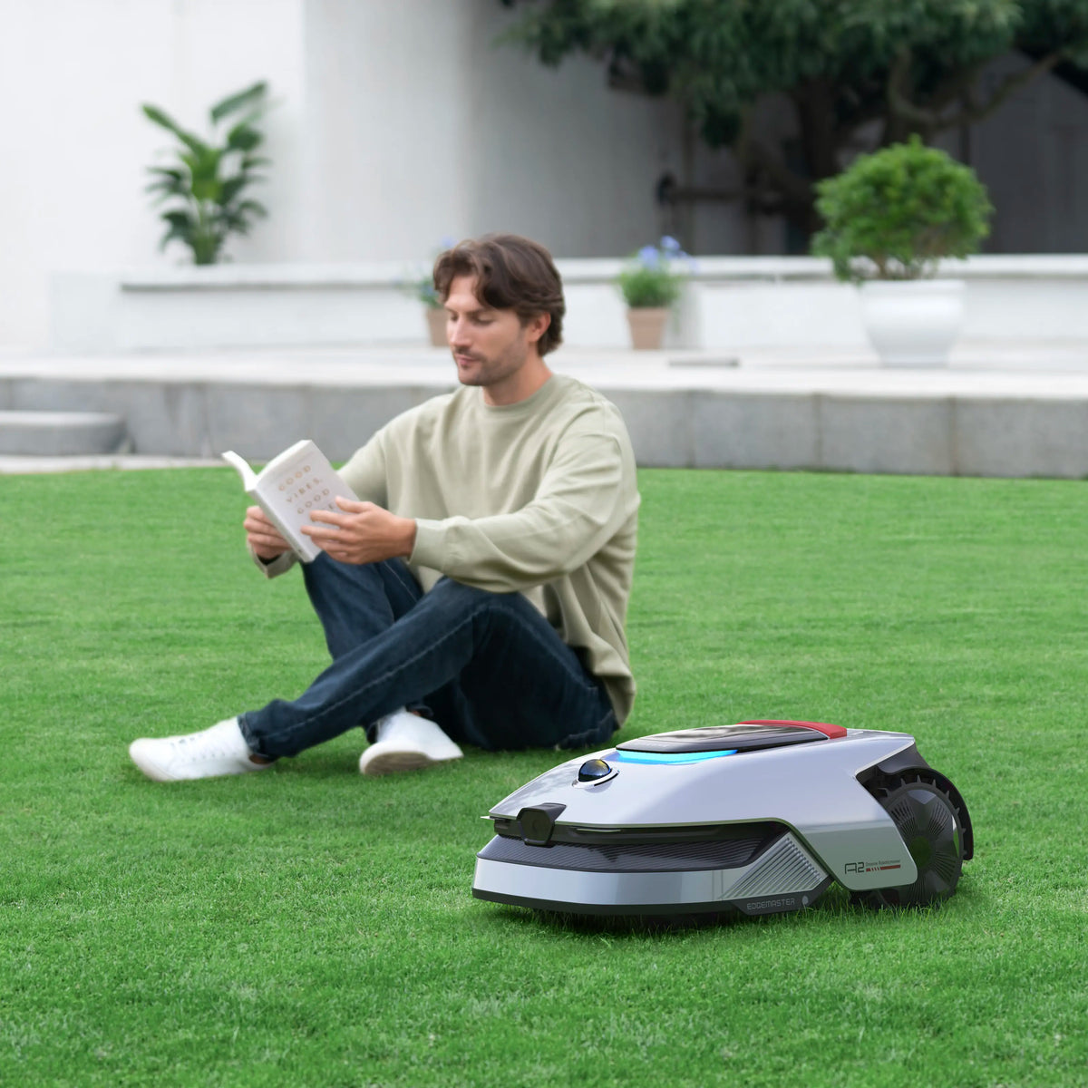 Dreame A2 robotplæneklipper til 3.000 m² med OmniSense 2.0 på en græsplæne med en person i baggrunden.