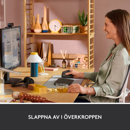 Logitech Lift – en vertikal, ergonomisk mus i farven grafit ved et skrivebord.