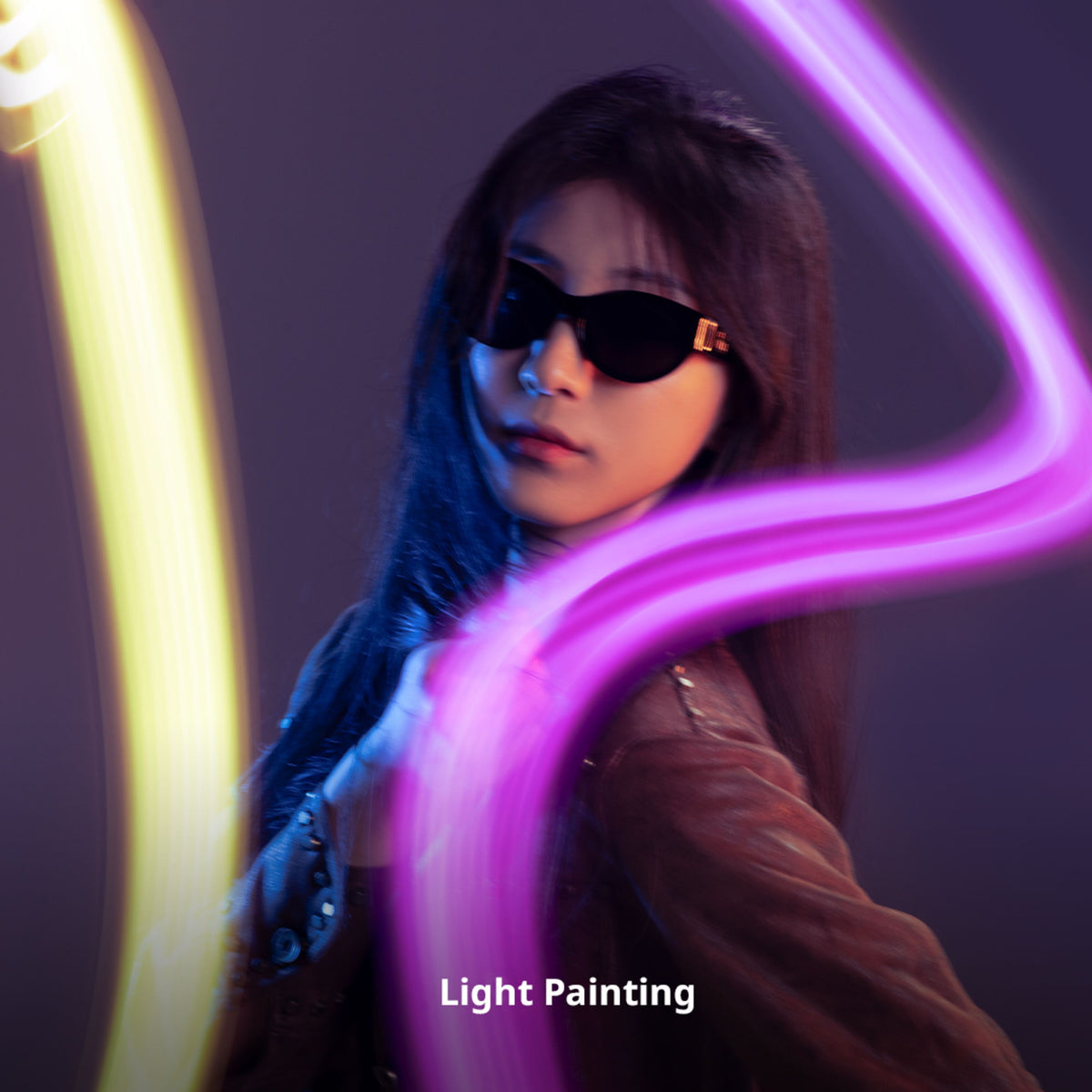 Person med solbriller og SmallRig Vibe P108 Pro RGBWW LED-lys, 2500–6500 K, med tekst i gul og lyserød light painting.