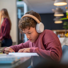 Dreng med beige Philips trådløse over-ear børnehovedtelefoner med støjreduktion, bordeaux sweatshirt, ses fra siden.