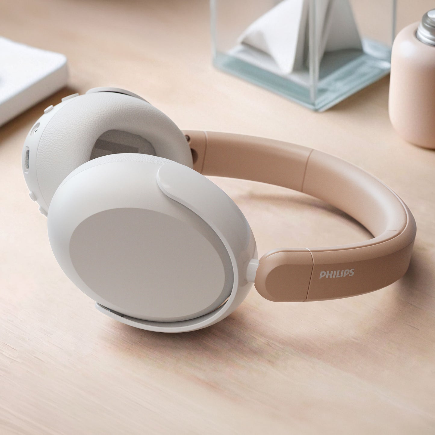 Philips trådløse over-ear hovedtelefoner til børn med støjreduktion i beige på lys træoverflade.