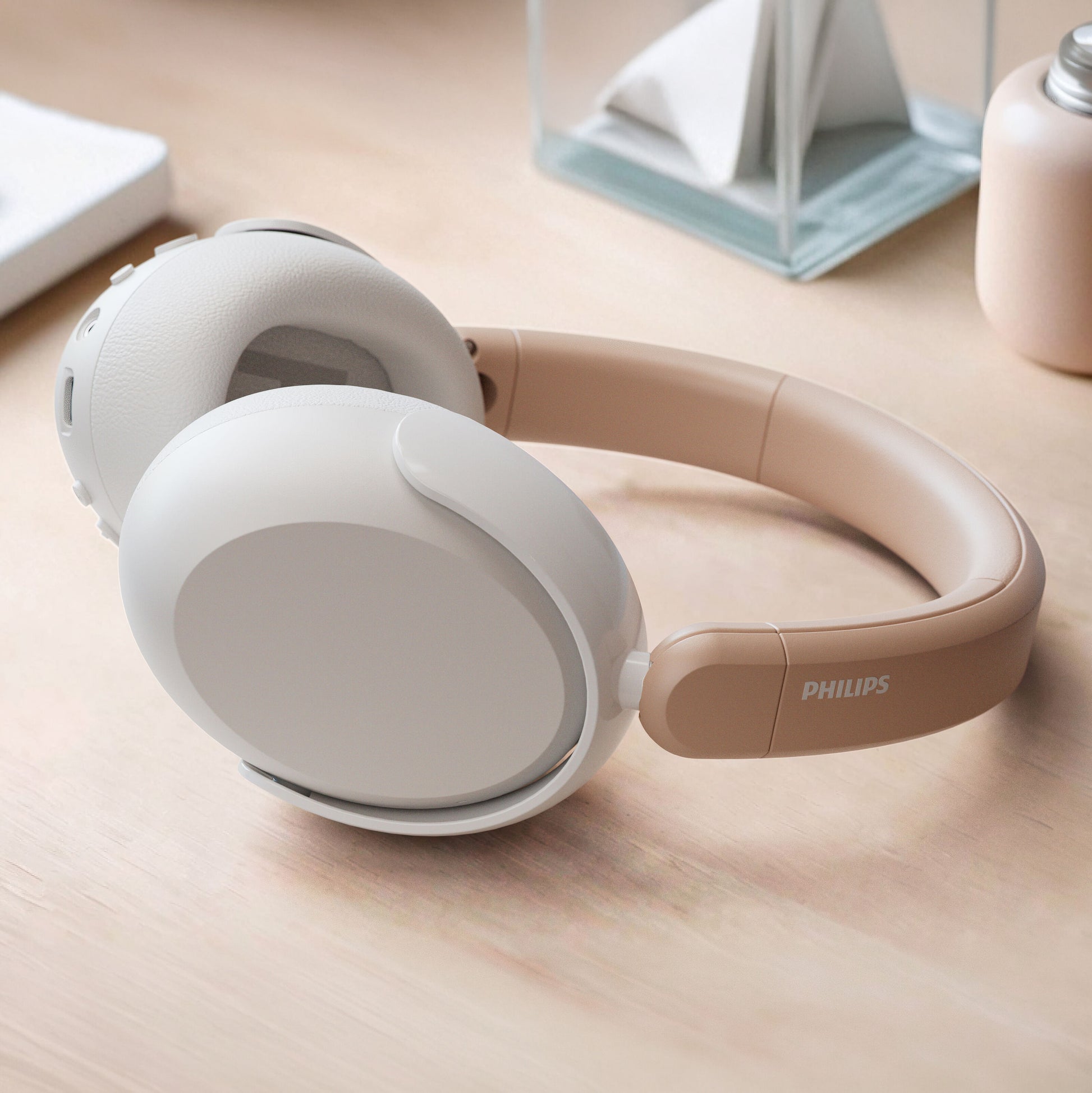 Philips trådløse over-ear hovedtelefoner til børn med støjreduktion i beige på lys træoverflade.