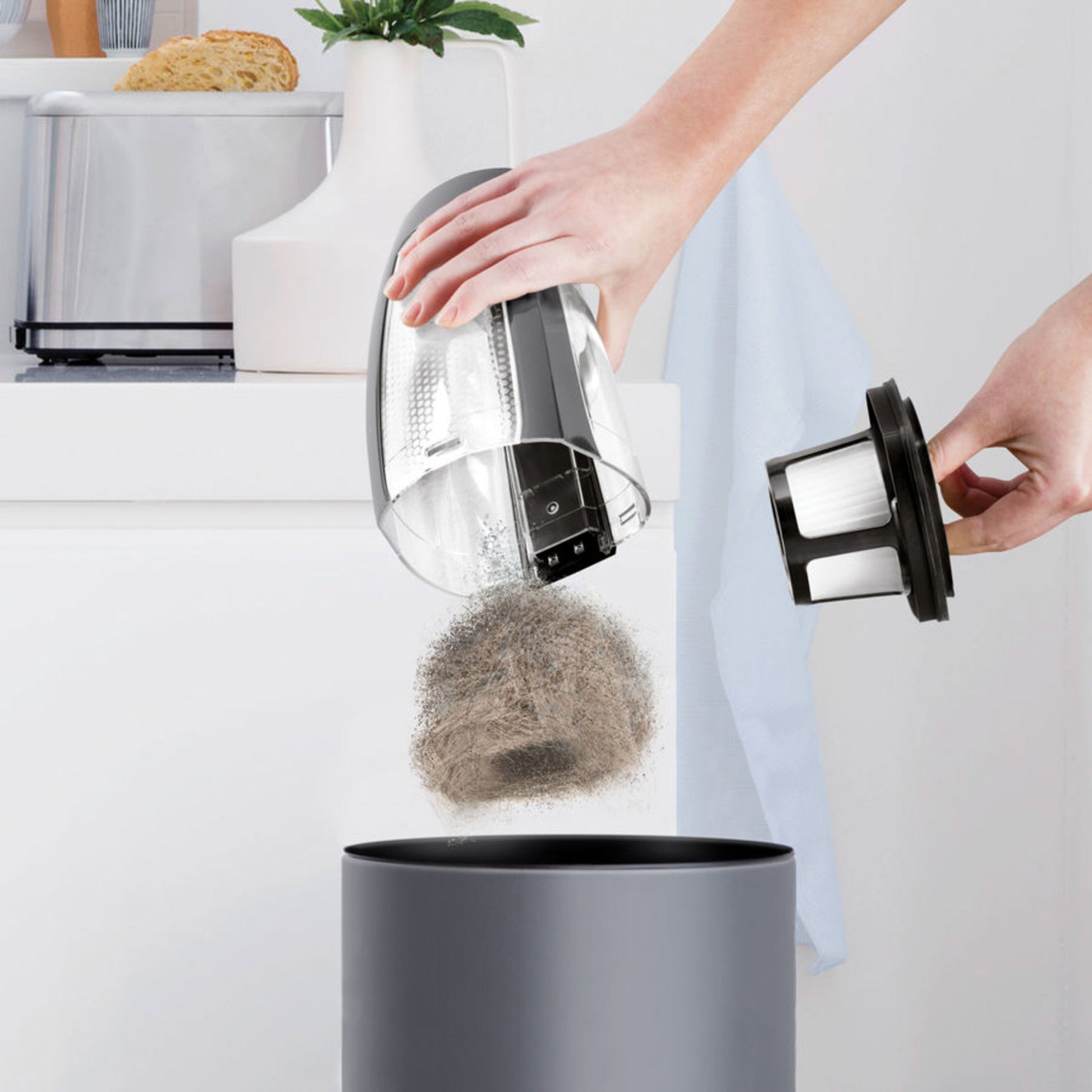 Bissel Pet Hair Eraser håndstøvsuger 14,4V tømmes for støv og hår i skraldespand, filter holdes over spand.