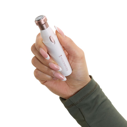 Remington BareMe Ansigtshårfjerner 2-i-1 Blush Rose holdes i hånd med manicurerede negle, grøn langærmet top.