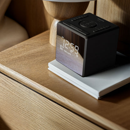 Philips R4600 DAB+ vækkeur, sølv, USB-C opladning, display viser 12:59, placeret på bog på trænatbord.