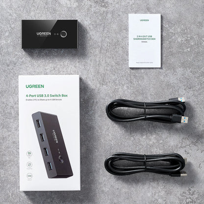 Ugreen USB 3.0-switch med 4 porte til 2 computere, 5 Gbps, inkl. 2 USB-kabler, brugervejledning og emballage.