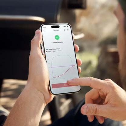 Typhur Sync Dual – trådløst grill- og stegetermometer til smartphone, to sondespidser, temperaturkurve og visning af »Cooking Complete«.