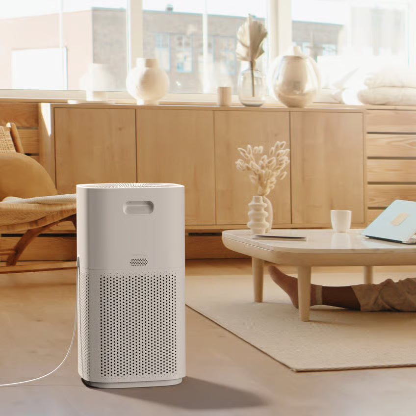 LEVOIT Core 600S hvid smart luftrenser med HEPA-filter på et lyst trægulv i en stor stue med moderne møbler og store vinduer.