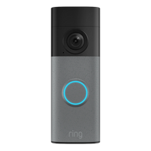 Ring Battery Video Doorbell Retinal 2K med gråmønstret kamera over en blå knap i et sølv-sort kabinet med bevægelsesdetektering.