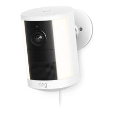 Ring Spotlight Cam Plug-in Retinal 2K, hvid med sort linsefelt, indbyggede spotlights, synligt strømkabel, logo under gitteret.