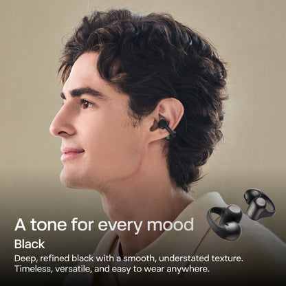 SHOKZ OpenDots 2 åbne klips-høretelefoner i sort, en ung person har dem på, ørepropper vist ved siden af.