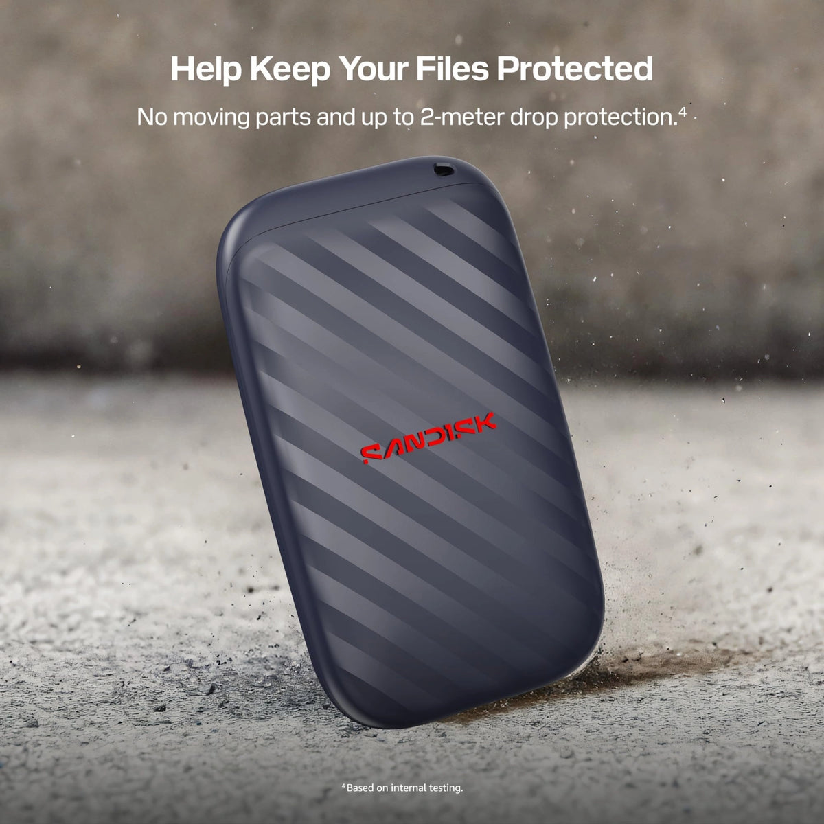 SanDisk bærbar SSD 1 TB USB-C 600 MB/s med stribet overflade på betonunderlag.