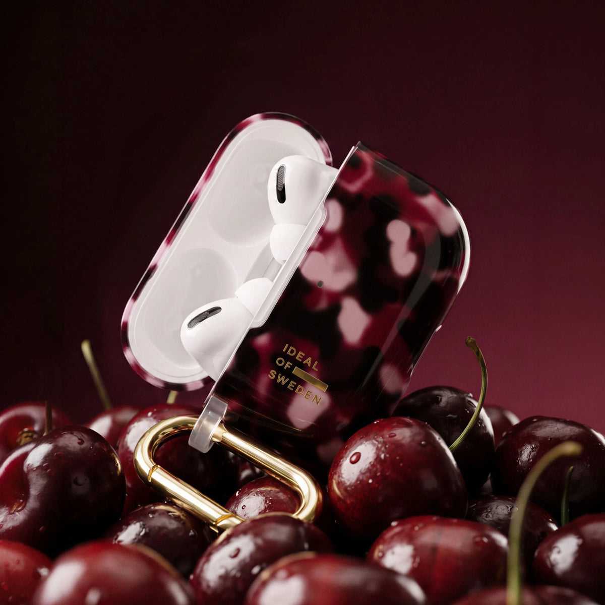 Gennemsigtigt iDeal of Sweden AirPods Pro 3-etui, Cherry Crush med kirsebærmønster og guldkarabinhage på kirsebær.