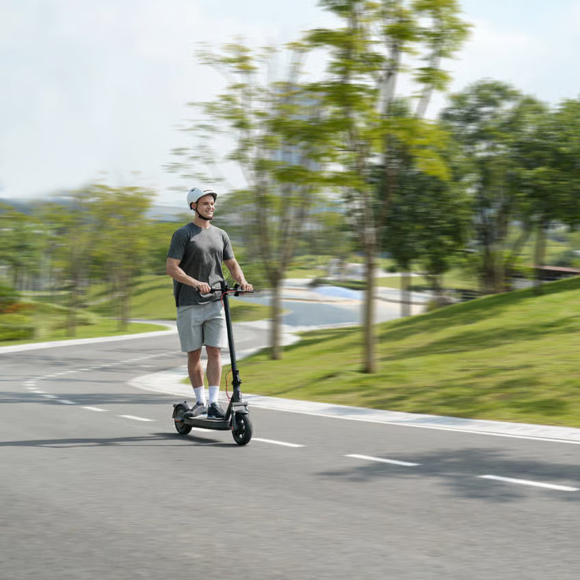 Mand med hvid hjelm på en Xiaomi Electric Scooter Elite NE el-løbehjul på en sti.
