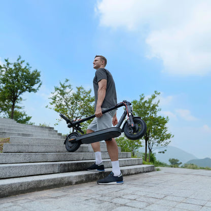 Mand bærer den sammenklappelige Xiaomi Electric Scooter Elite NE-løbehjul, 20 km/t, op ad en stentrappe.