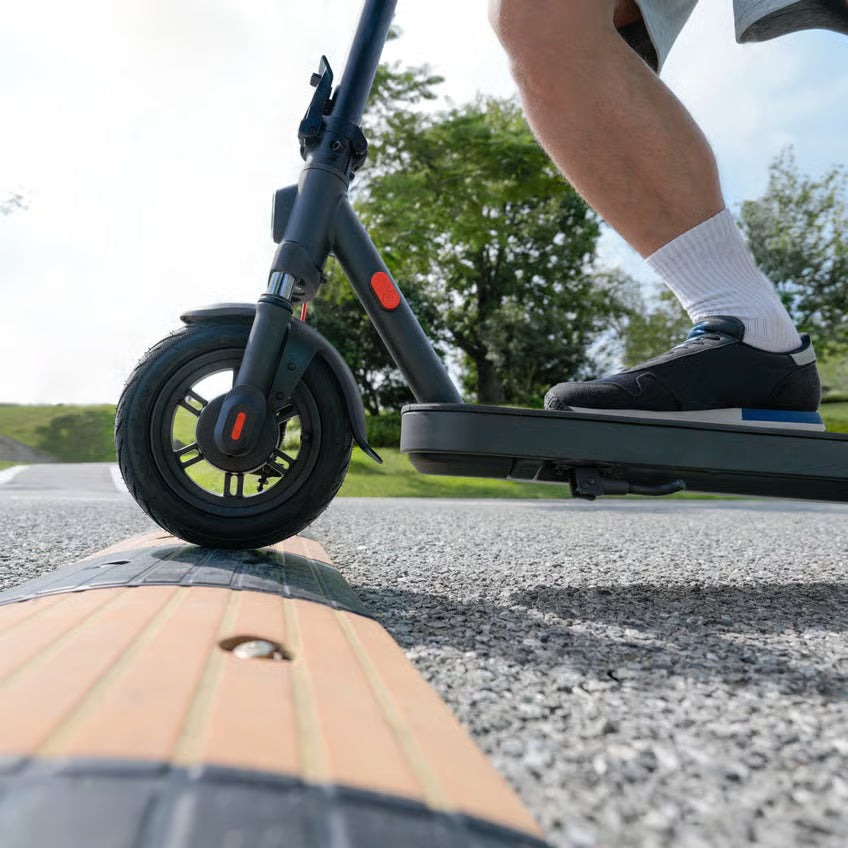 Xiaomi Electric Scooter Elite NE – elløbehjul på asfaltvej over en fartbump.