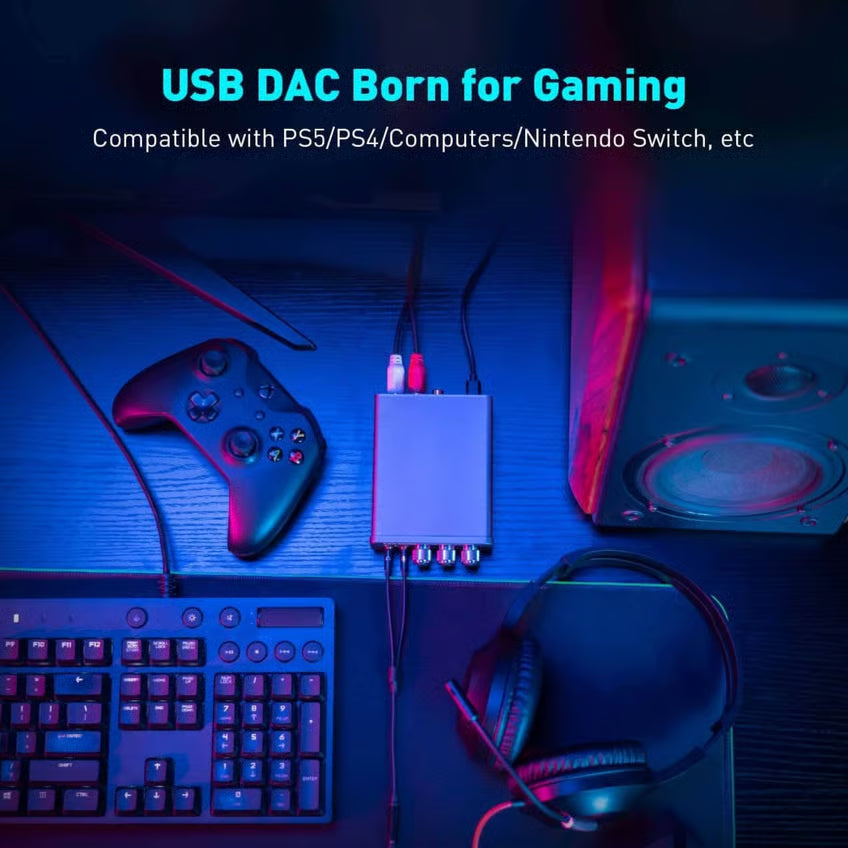 Fosi Audio K5 Pro gaming-DAC og hovedtelefonforstærker på skrivebordet sammen med kabler, controller, tastatur og headset.