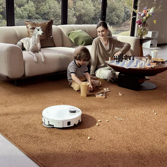 Hvid Dreame X60 Pro Ultra Complete robotstøvsuger med moppefunktion kører på et brunt tæppe.