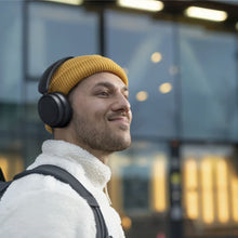 Person med gul hue og sorte trådløse over-ear-hovedtelefoner fra Philips 5000-serien.