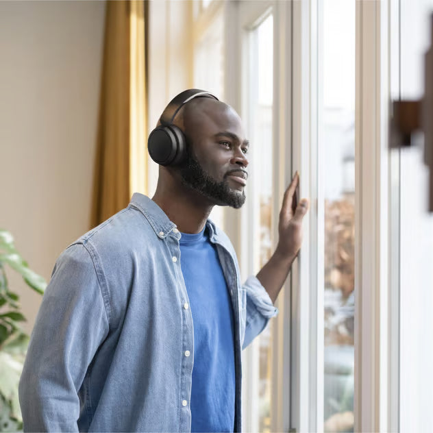 Sorter Philips 5000-seriens trådløse over-ear-hovedtelefoner efter mand ved vinduet.