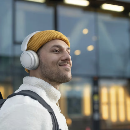 Hvide Philips 5000-serie trådløse over-ear-hovedtelefoner, som en person har på sig udendørs.