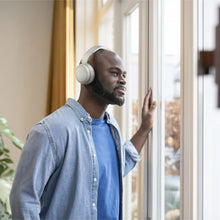 Hvide Philips 5000-serie trådløse over-ear-hovedtelefoner på en mand ved vinduet.