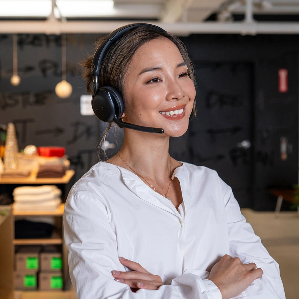 Kvinde med sort JLab GO Work 3 trådløst on-ear-headset med boom-mikrofon og flip-to-mute-funktion.