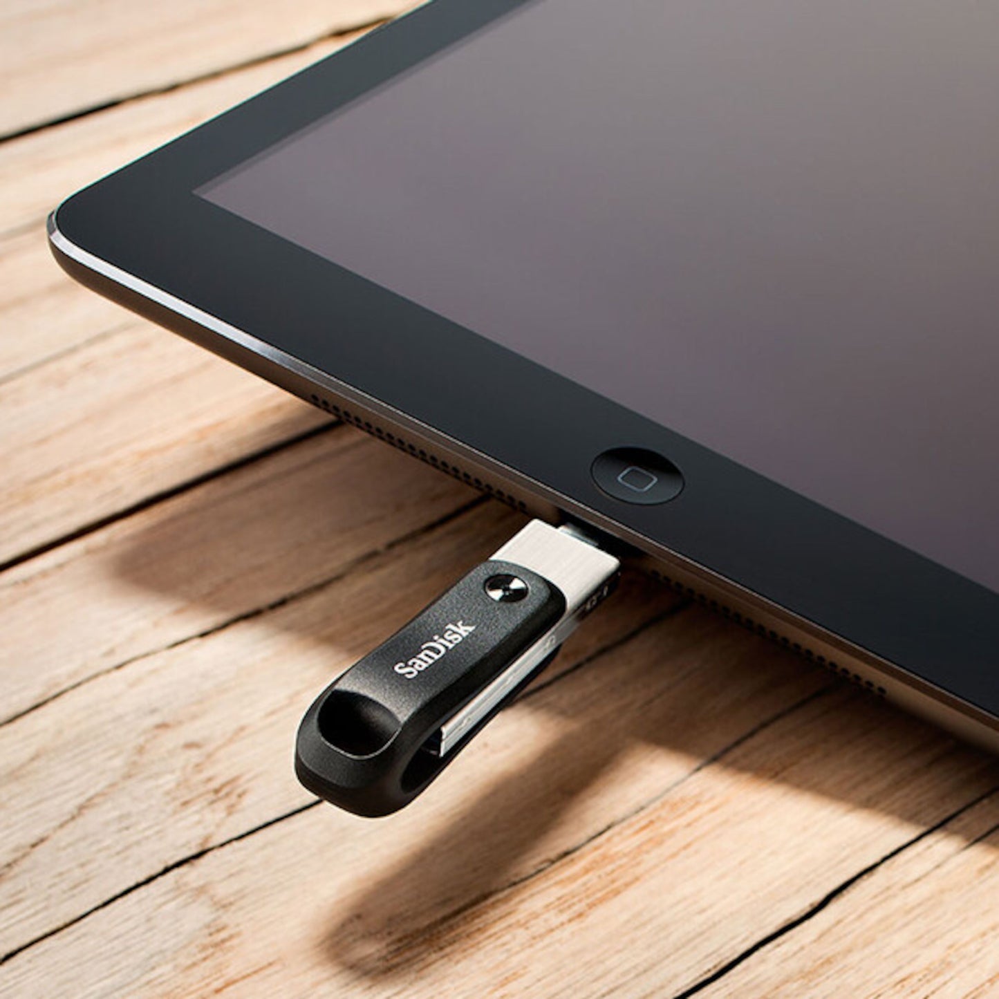 Sandisk iXpand Go USB-nøgle med Lightning-stik 256 GB tilsluttet tablet, vises på træoverflade.