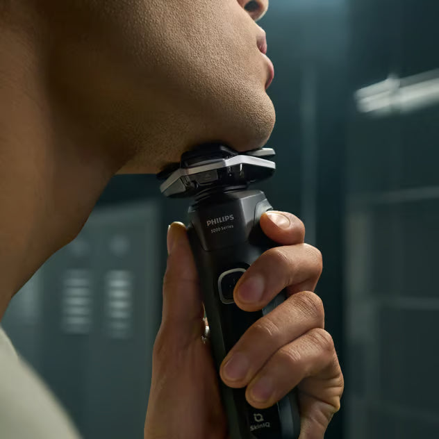 Mand bruger en sort Philips Shaver Series 5000 S5898/35 roterende elektrisk barbermaskine langs kæbelinjen.