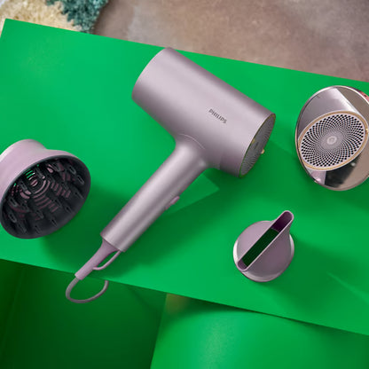 Philips 7000-serien BHD723/10 hårtørrer i lilla med to dyser og en diffuser på en grøn overflade.