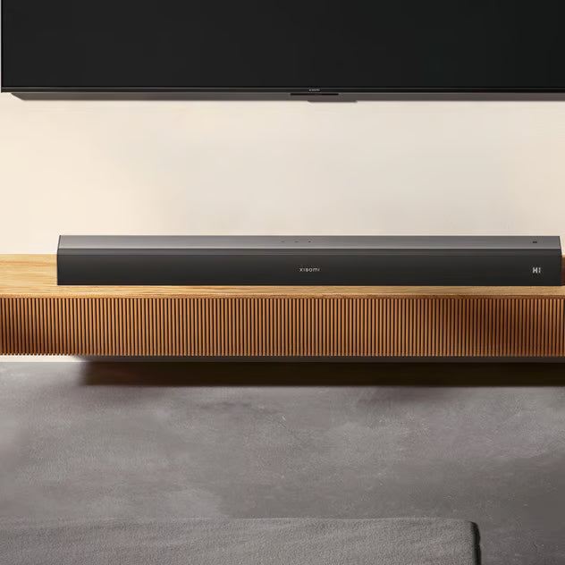 Xiaomi Soundbar Pro 2.0, sort, 84 W, Dolby Audio og HDMI eARC placeret på et træmøbel under et væghængt tv.