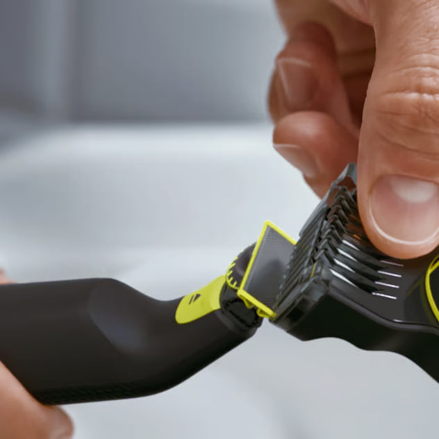 Hænder monterer en justerbar limegrøn og sort trimmerkam på Philips OneBlade Pro 360 QP6542/15 skægtrimmer.