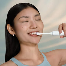 En kvinde børster tænder med en hvid Philips Sonicare 5300 HX7108/01 sonisk elektrisk tandbørste med trykføler.