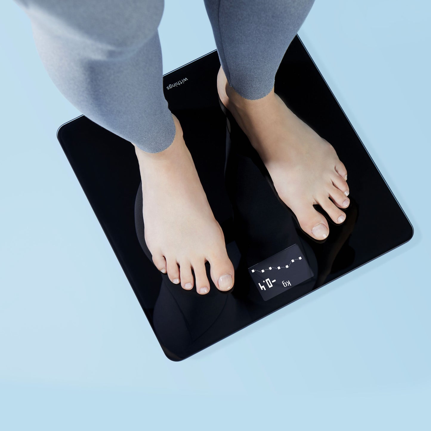 Withings kropsvægt med wifi, sort, digitalt display viser vægt, person står på vægten iført grå leggings.
