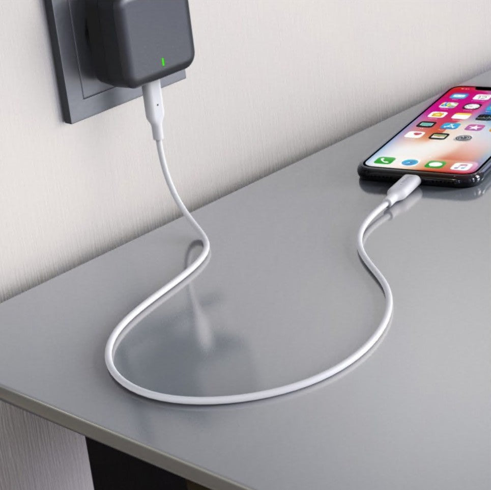 IPhone oplades med USB-C til Lightning-kabel (MFi, hvid, 1 m) tilsluttet vægadapter, skærmen viser appikoner.