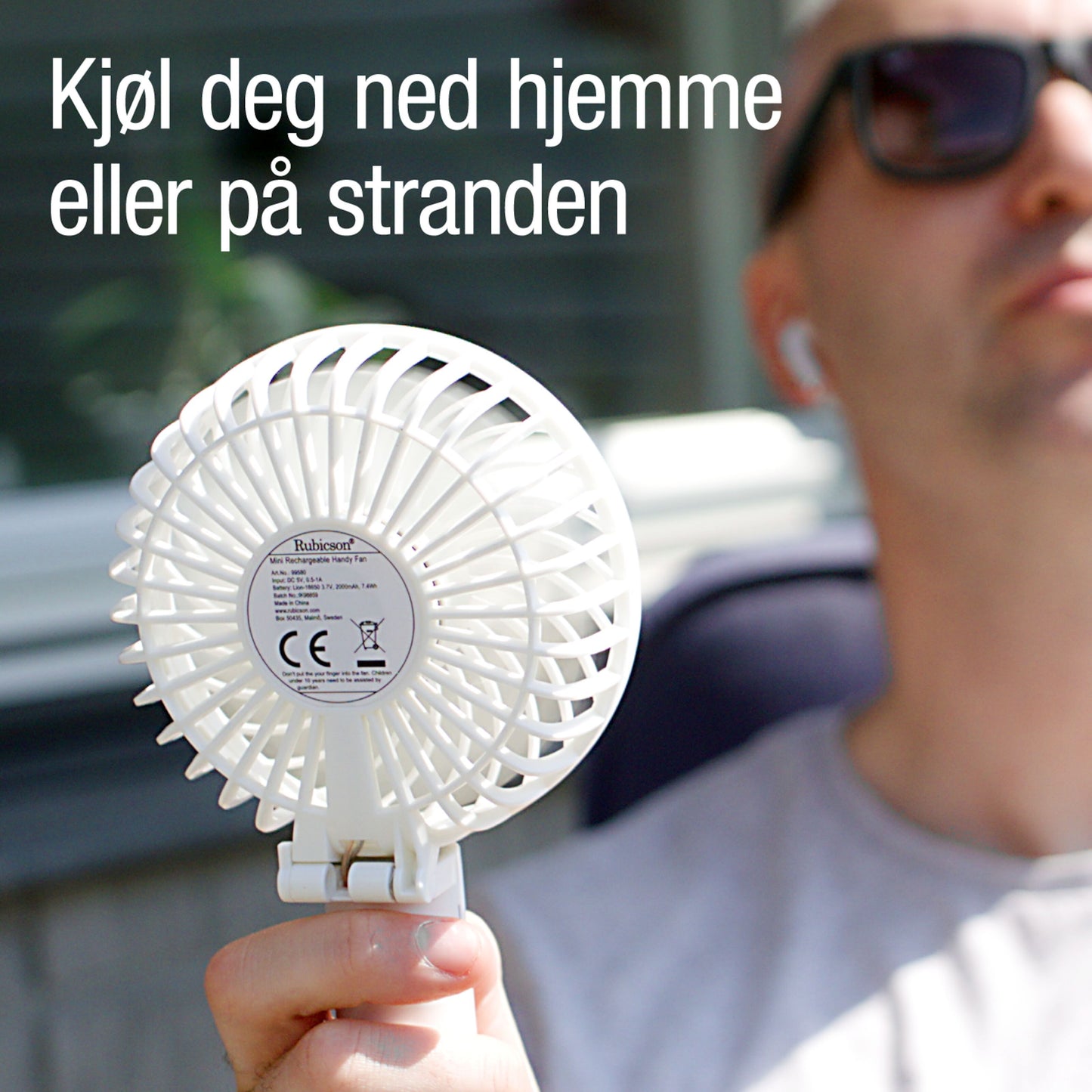 Rubicson bærbar ventilator med genopladeligt batteri, mand med solbriller holder den, norsk tekst: Kjøl dig ned hjemme eller på stranden.