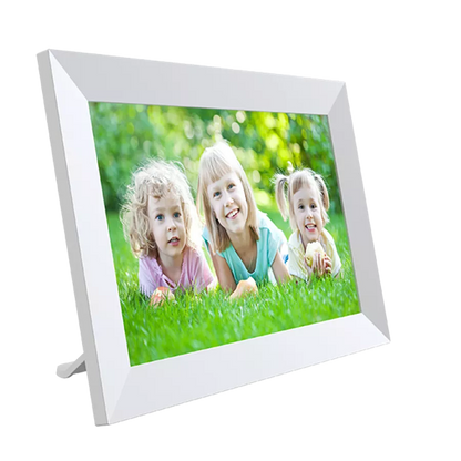Denver PFF-1064W digital fotoramme Frameo 10.1" hvid IPS touchscreen viser tre lyshårede børn på grøn græs.